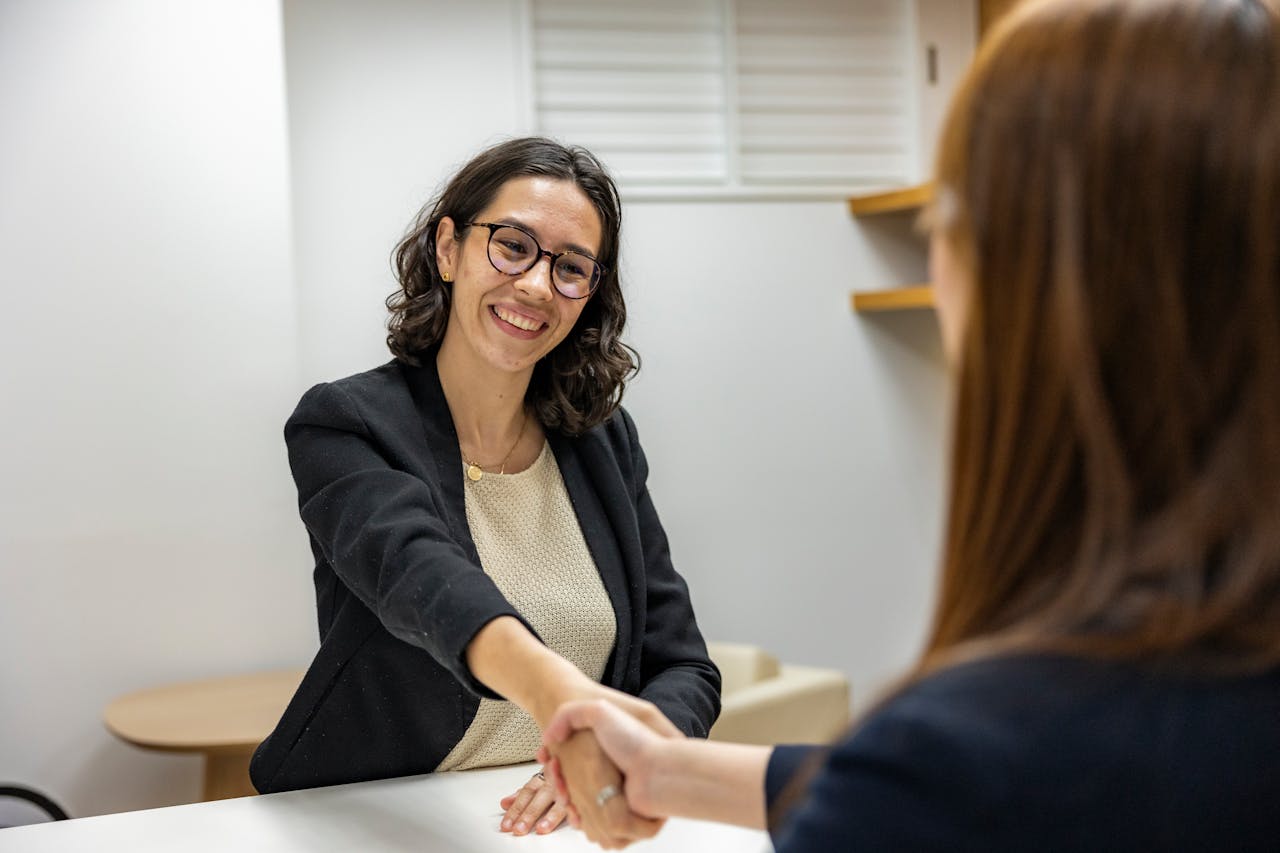 services-01 Businesswomen shaking hands in an office, representing a successful job interview or partnership.